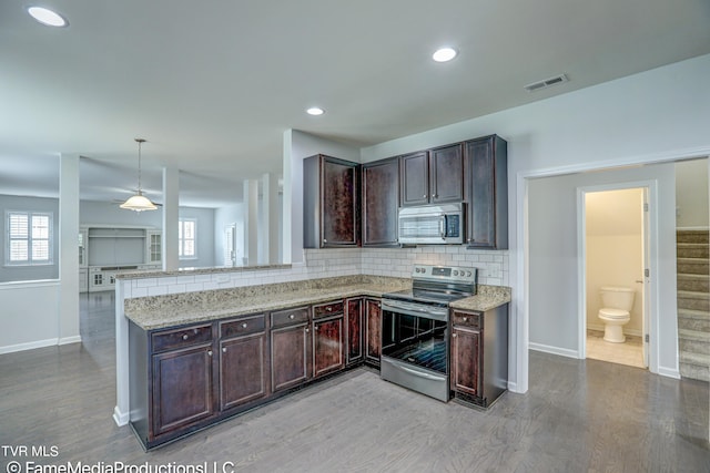 kitchen featuring pendant lighting, light hardwood / wood-style floors, kitchen peninsula, backsplash, and appliances with stainless steel finishes