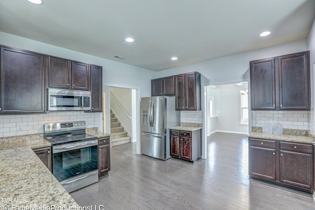 kitchen featuring decorative backsplash, stainless steel appliances, light stone counters, and light hardwood / wood-style floors