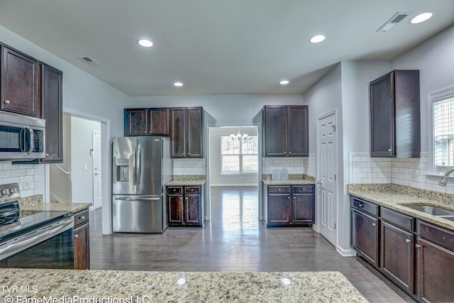 kitchen with light stone counters, sink, tasteful backsplash, dark wood-type flooring, and stainless steel appliances