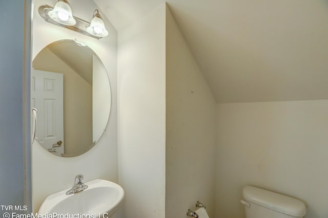 bathroom with lofted ceiling, toilet, and sink