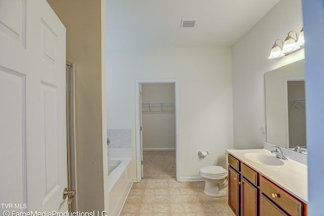 bathroom with tiled bath, vanity, and toilet