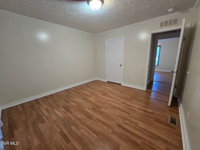 empty room with hardwood / wood-style flooring, a textured ceiling, and ornamental molding