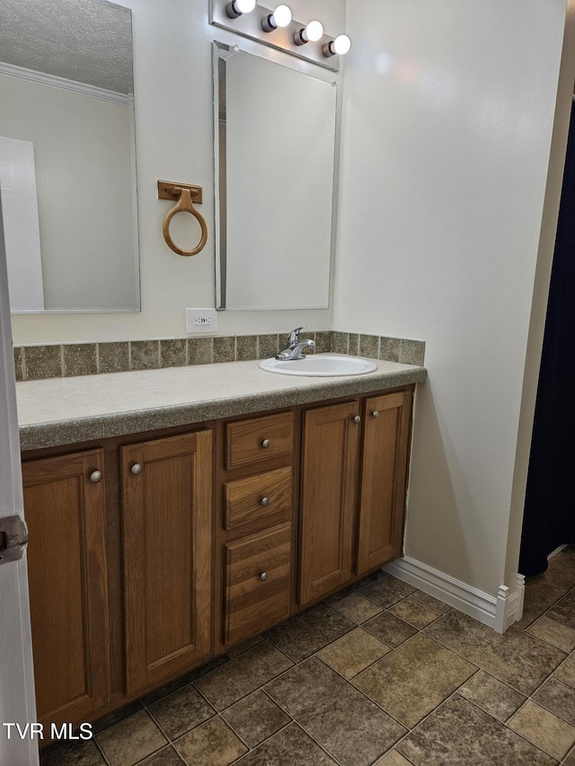 bathroom with ornamental molding, vanity, and a textured ceiling