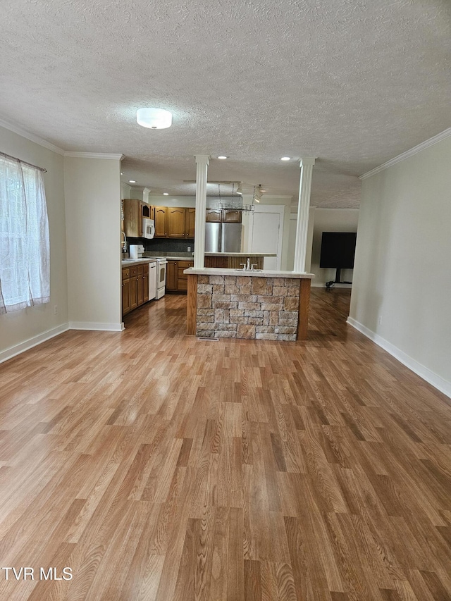 unfurnished living room with decorative columns, light hardwood / wood-style floors, a textured ceiling, and ornamental molding