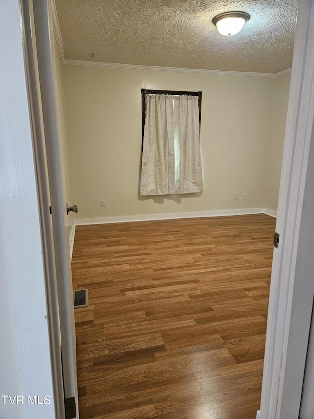 spare room with ornamental molding, hardwood / wood-style floors, and a textured ceiling