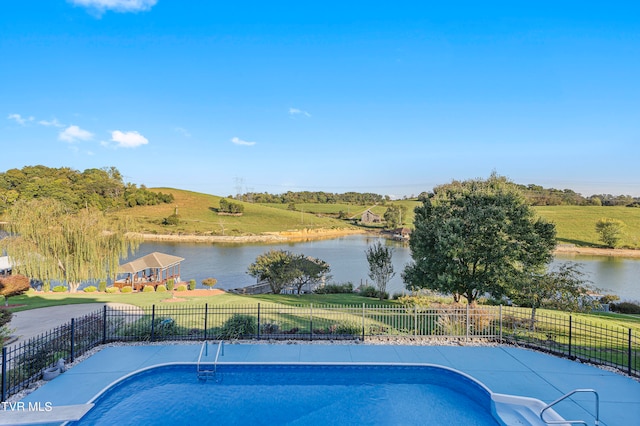 view of swimming pool with a water view, a yard, and a rural view