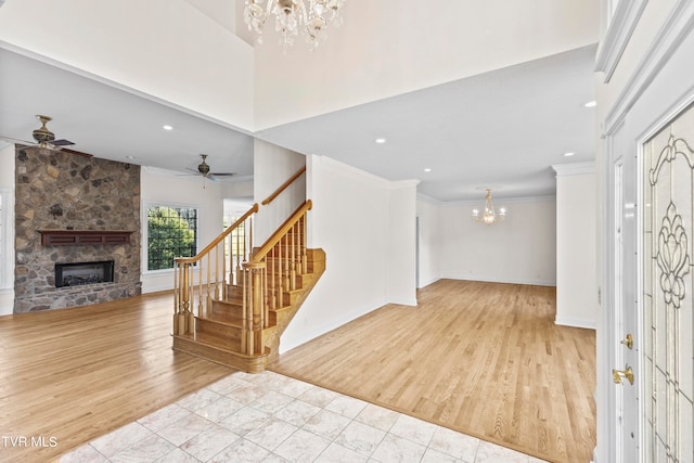 entrance foyer with a fireplace, ceiling fan with notable chandelier, light hardwood / wood-style floors, and crown molding