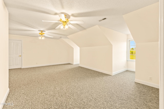 additional living space featuring ceiling fan, vaulted ceiling, carpet, and a textured ceiling