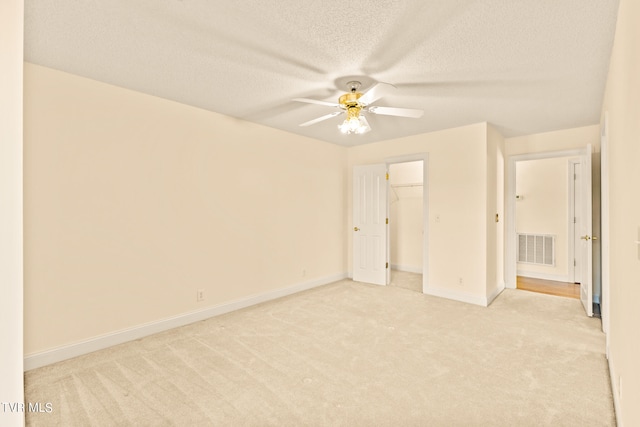 unfurnished bedroom with ceiling fan, a textured ceiling, a closet, and light carpet