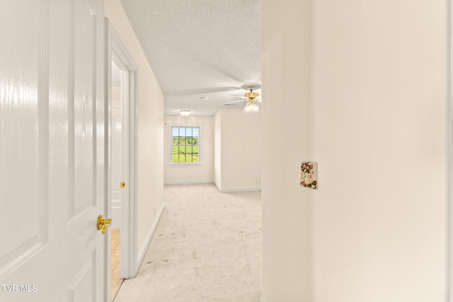 hall featuring light carpet and a textured ceiling