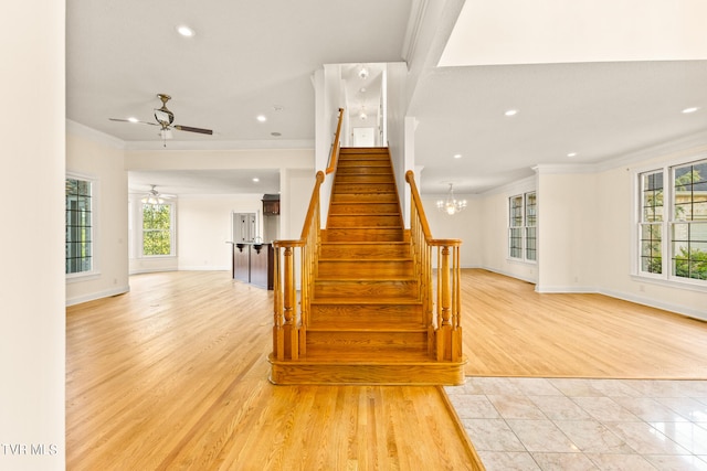 stairway with ceiling fan with notable chandelier, ornamental molding, and hardwood / wood-style flooring