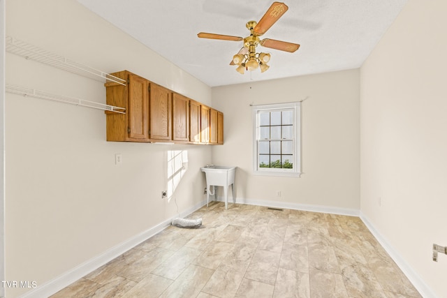 washroom with ceiling fan, hookup for an electric dryer, sink, and cabinets