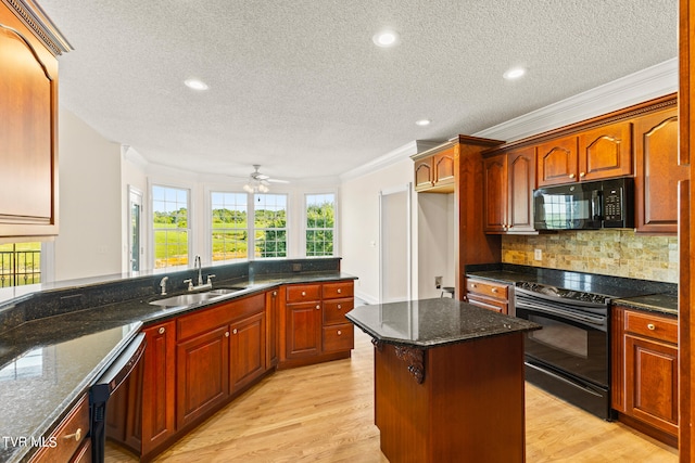 kitchen with dark stone countertops, light hardwood / wood-style floors, sink, and black appliances