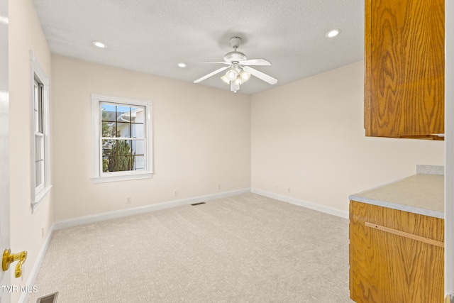 spare room with light colored carpet, a textured ceiling, and ceiling fan