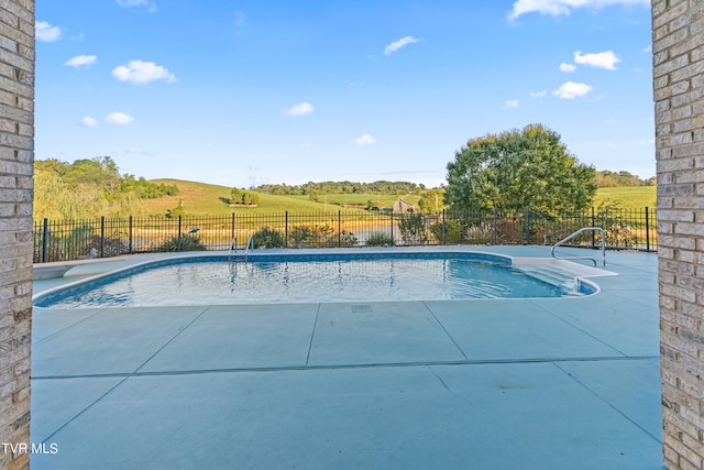 view of pool with a rural view and a patio