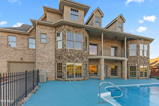 back of house featuring cooling unit, a fenced in pool, and a balcony