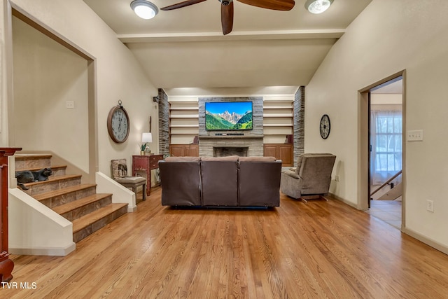 living room featuring ceiling fan, a fireplace, light hardwood / wood-style floors, and vaulted ceiling