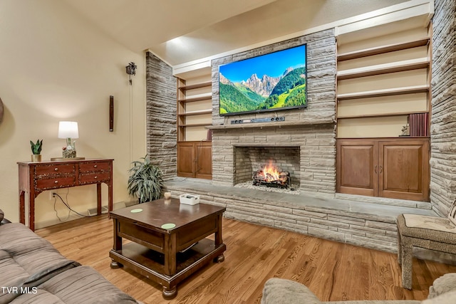 living room with lofted ceiling, a fireplace, and light hardwood / wood-style flooring