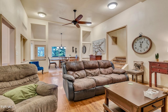 living room featuring built in features, light hardwood / wood-style floors, and ceiling fan with notable chandelier