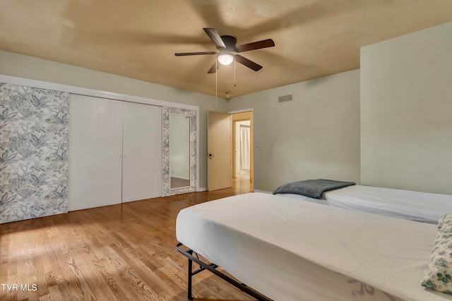 bedroom featuring hardwood / wood-style flooring, ceiling fan, and a closet