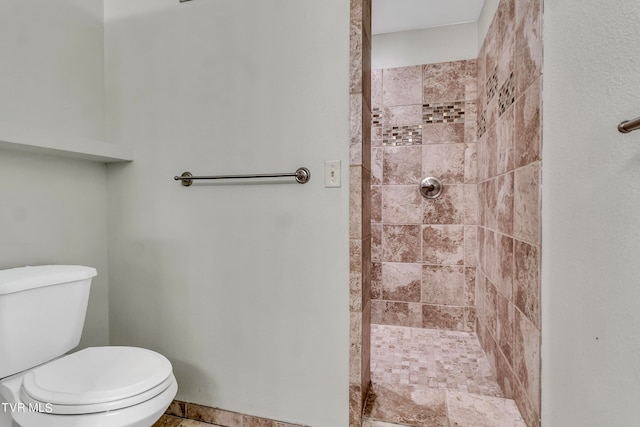 bathroom featuring tiled shower and toilet