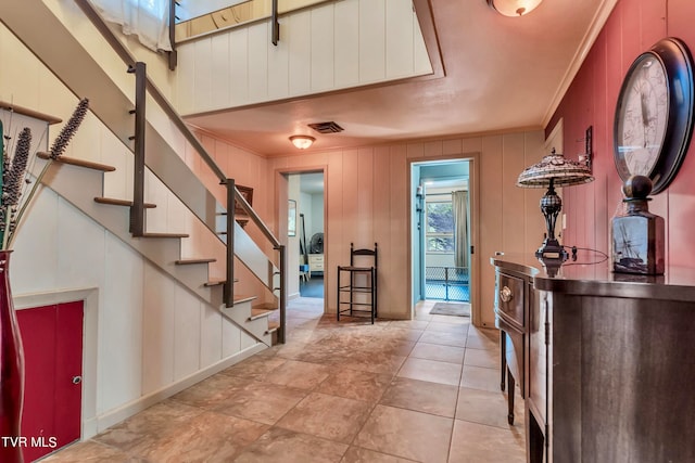 foyer entrance featuring crown molding and wooden walls