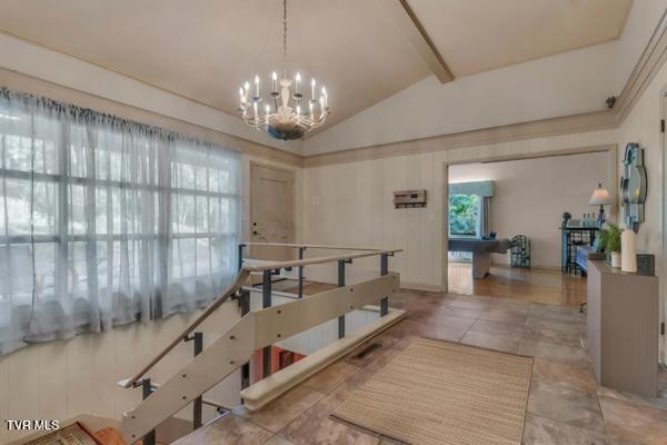 dining space with lofted ceiling with beams and an inviting chandelier