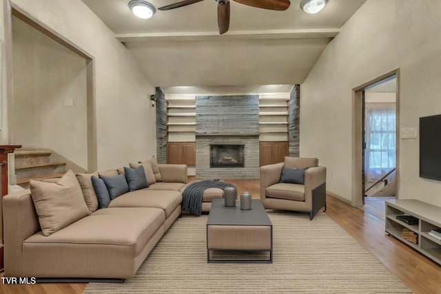 living room featuring light hardwood / wood-style floors, ceiling fan, and a tiled fireplace