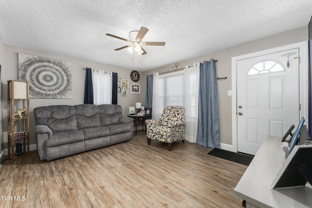 living room with ceiling fan, a textured ceiling, and light hardwood / wood-style flooring