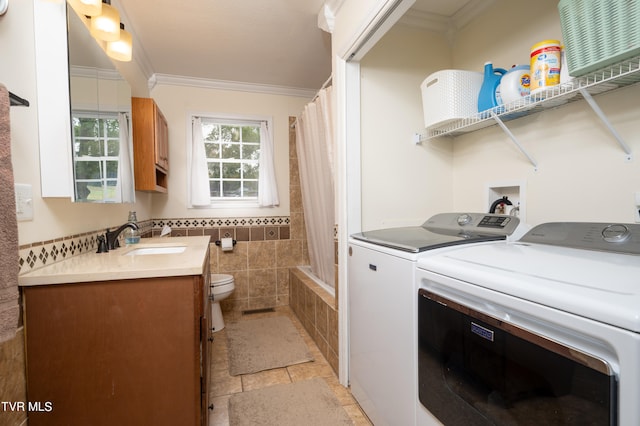 laundry area with ornamental molding, tile walls, separate washer and dryer, and sink