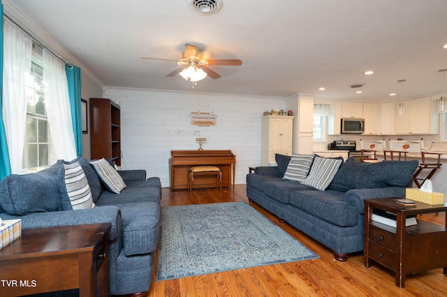 living room featuring light wood-type flooring, crown molding, and ceiling fan