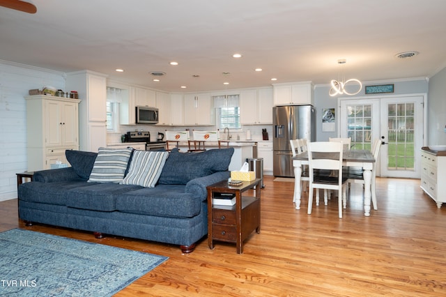 living room featuring light wood-type flooring, ornamental molding, sink, and french doors