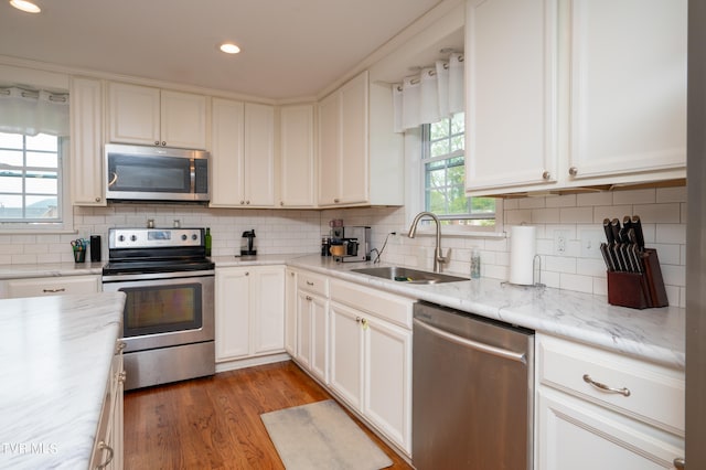 kitchen featuring light stone counters, appliances with stainless steel finishes, hardwood / wood-style floors, and decorative backsplash