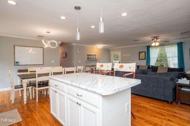 kitchen with light hardwood / wood-style flooring, white cabinets, a center island, and hanging light fixtures