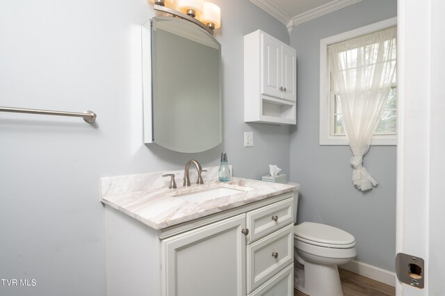 bathroom featuring wood-type flooring, vanity, crown molding, and toilet