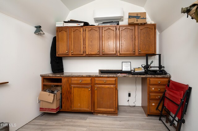 kitchen with lofted ceiling, light hardwood / wood-style floors, and an AC wall unit