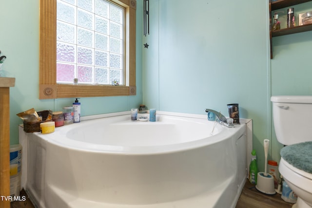 bathroom featuring a washtub, hardwood / wood-style floors, toilet, and a wealth of natural light