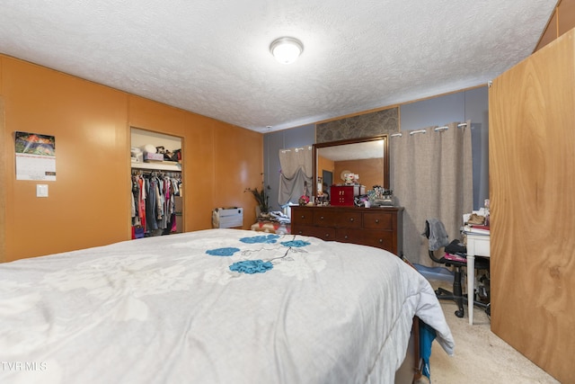 bedroom featuring a walk in closet, light carpet, a closet, and a textured ceiling