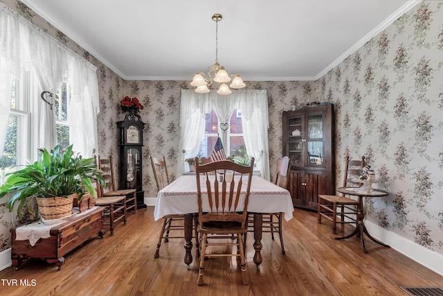 dining area featuring an inviting chandelier, hardwood / wood-style flooring, and ornamental molding