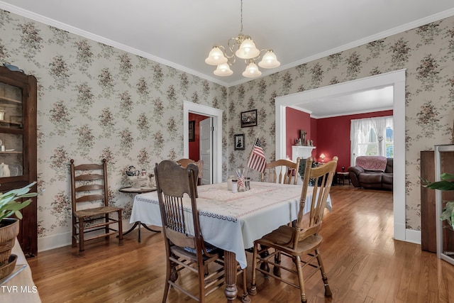 dining room with wood-type flooring, an inviting chandelier, and ornamental molding