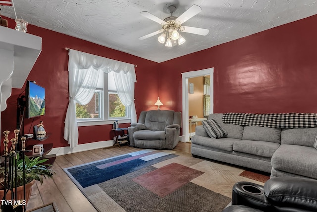 living room with ceiling fan, a textured ceiling, and light wood-type flooring