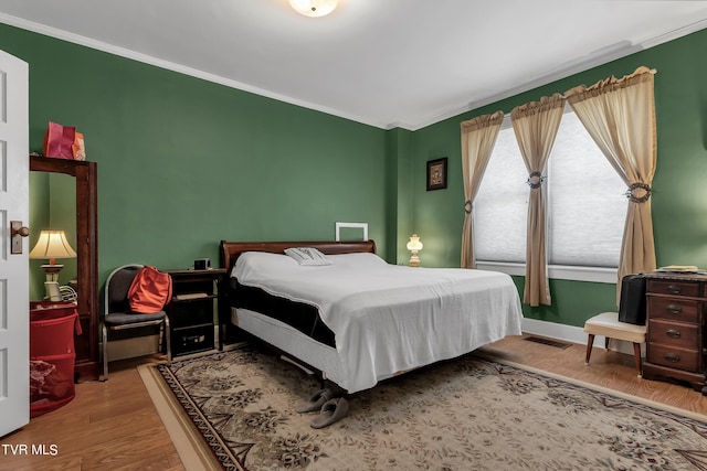 bedroom with hardwood / wood-style flooring and ornamental molding