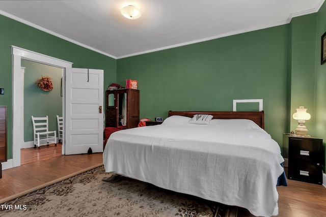 bedroom with ornamental molding, vaulted ceiling, and hardwood / wood-style floors