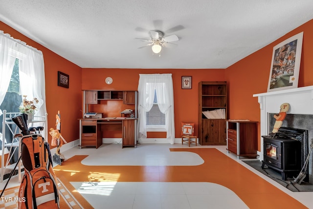 interior space with ceiling fan, a textured ceiling, and a wood stove