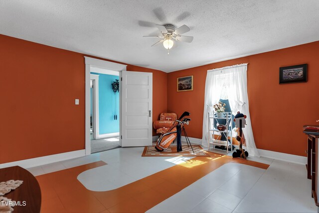 workout area featuring ceiling fan and a textured ceiling