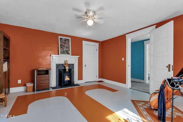 interior space featuring a textured ceiling, ceiling fan, and a wood stove