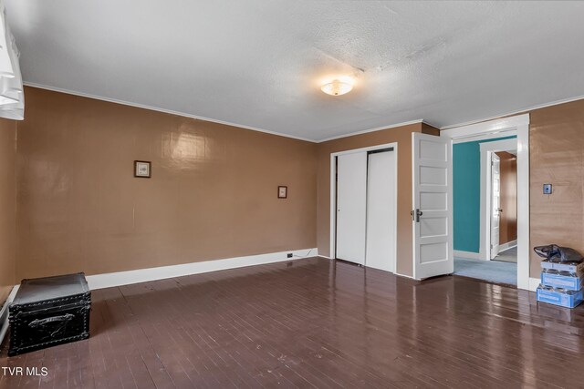 interior space featuring ornamental molding, a textured ceiling, a closet, and dark hardwood / wood-style flooring