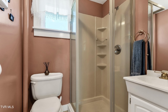 bathroom featuring a shower with door, vanity, and toilet