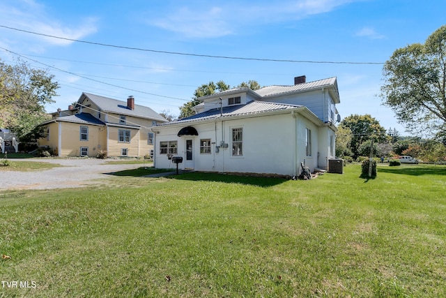 view of front of house with central AC unit and a front yard