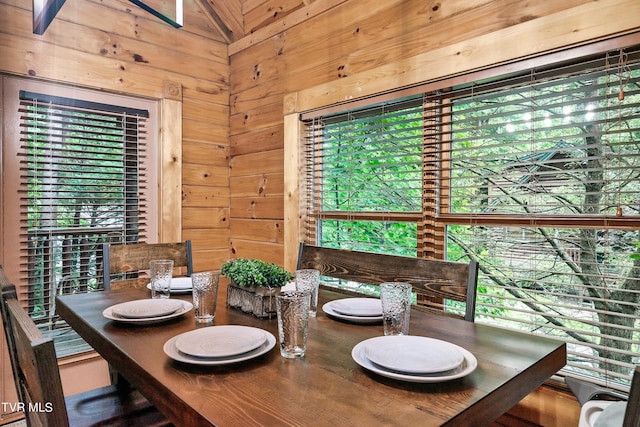 dining area featuring wooden walls and plenty of natural light